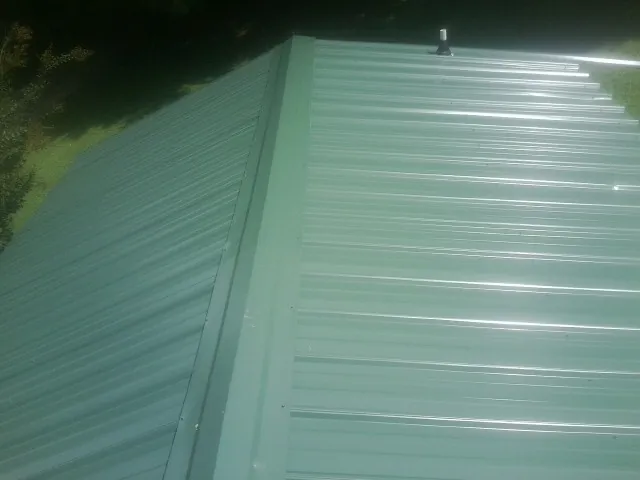 New green metal panels meeting at the ridge of a roof in Prairie