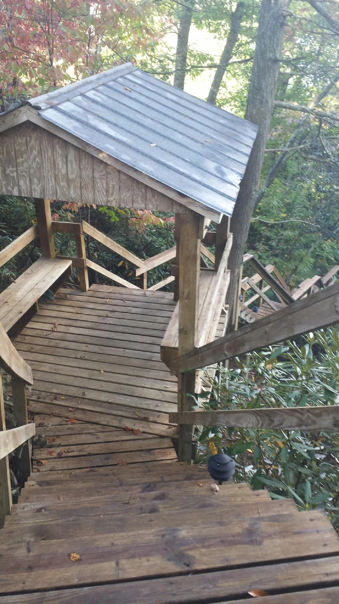 Metal roofed shelter over wooden steps on a wooded walkway — Skylight Repair & Installation work by our crew in Prairie