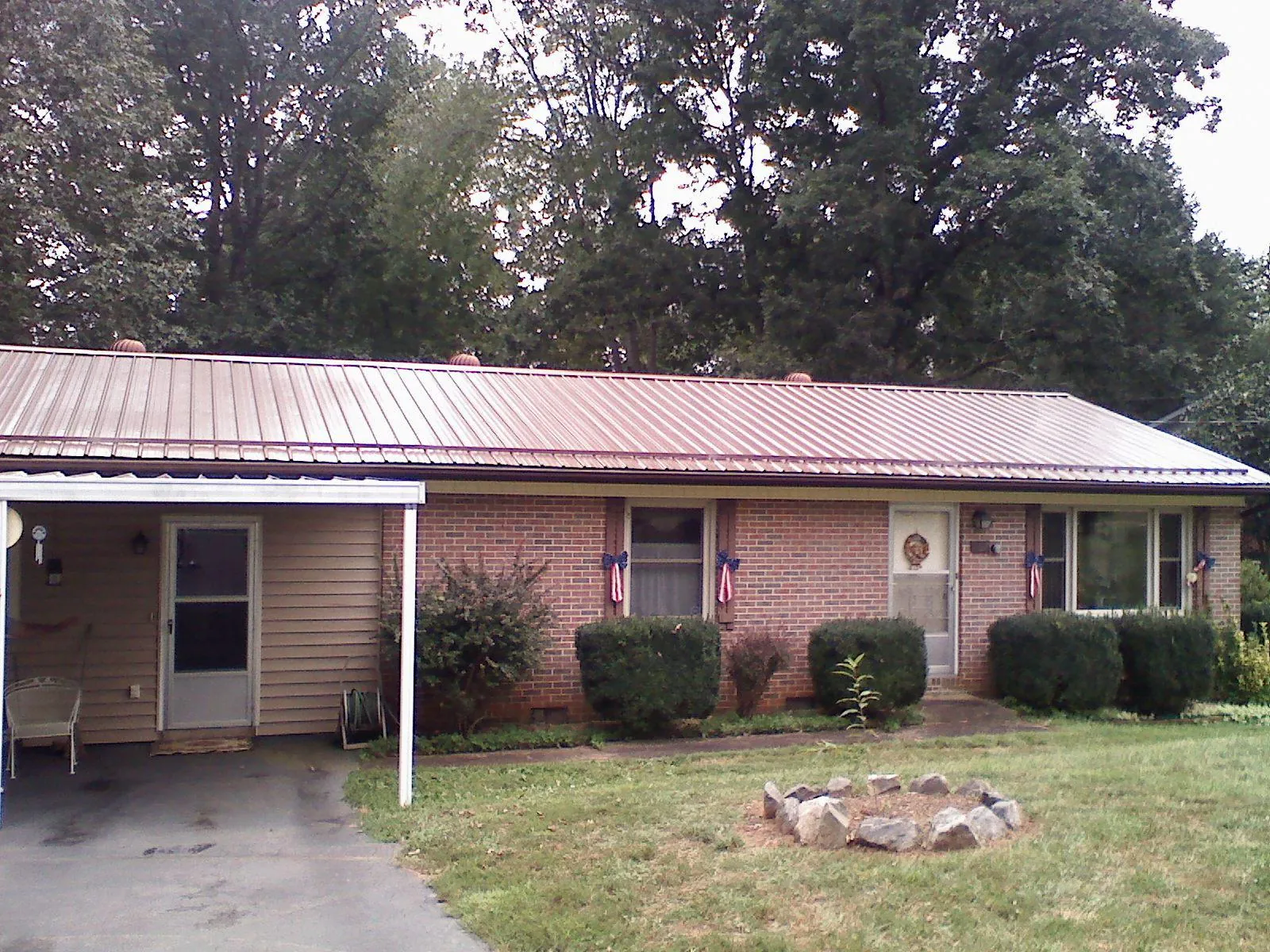 Bronze metal roof and carport on a brick ranch home — Roof Repair work by our crew in Prairie