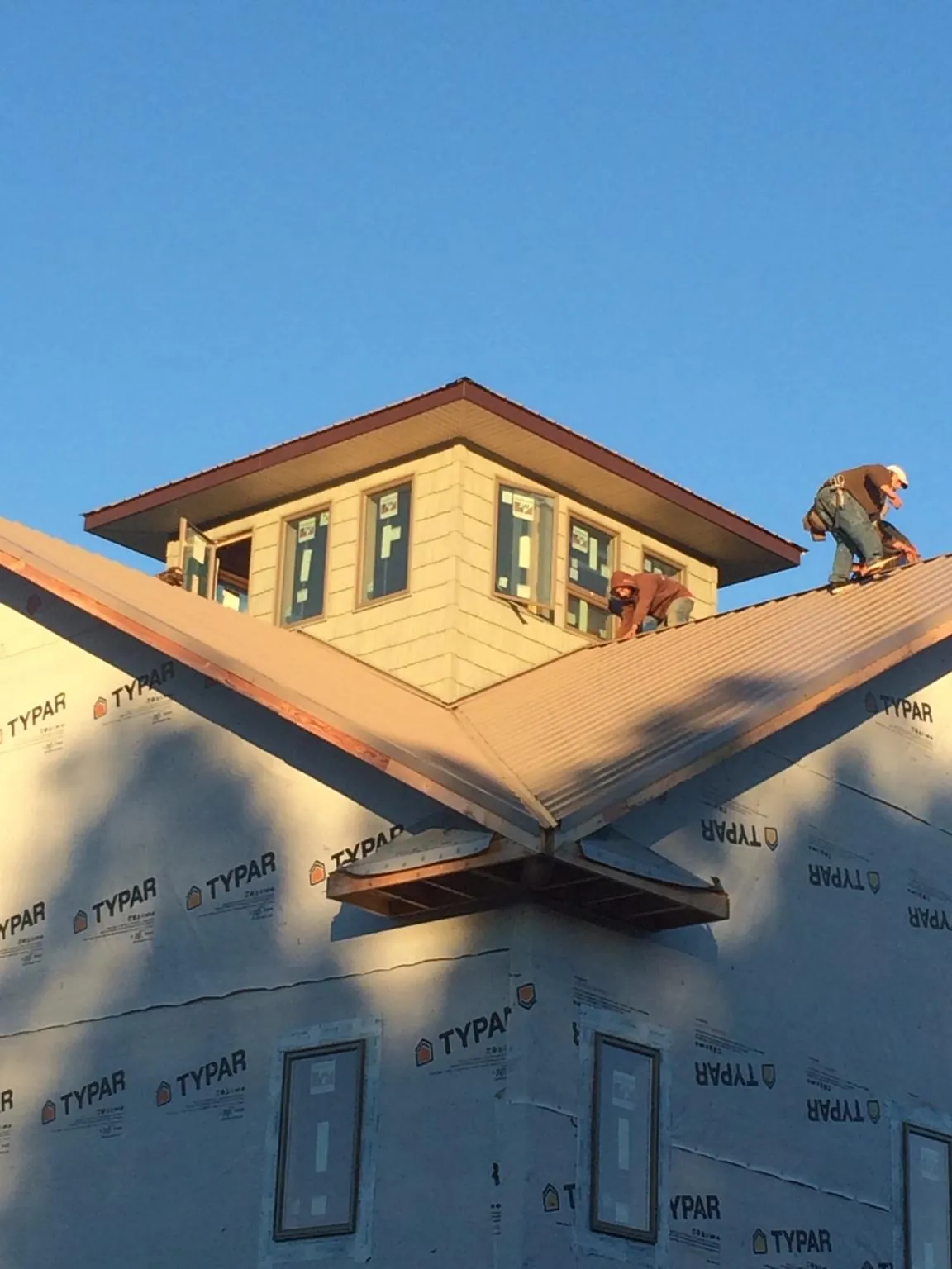 Roofers working around a rooftop cupola on a new metal roof at sunset — Roof Waterproofing in Prairie by Roofing Brothers